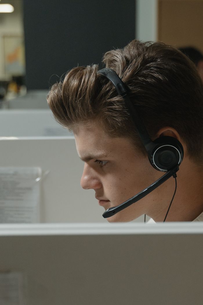 Services Close-up of a focused male call center agent wearing a black headset at work.